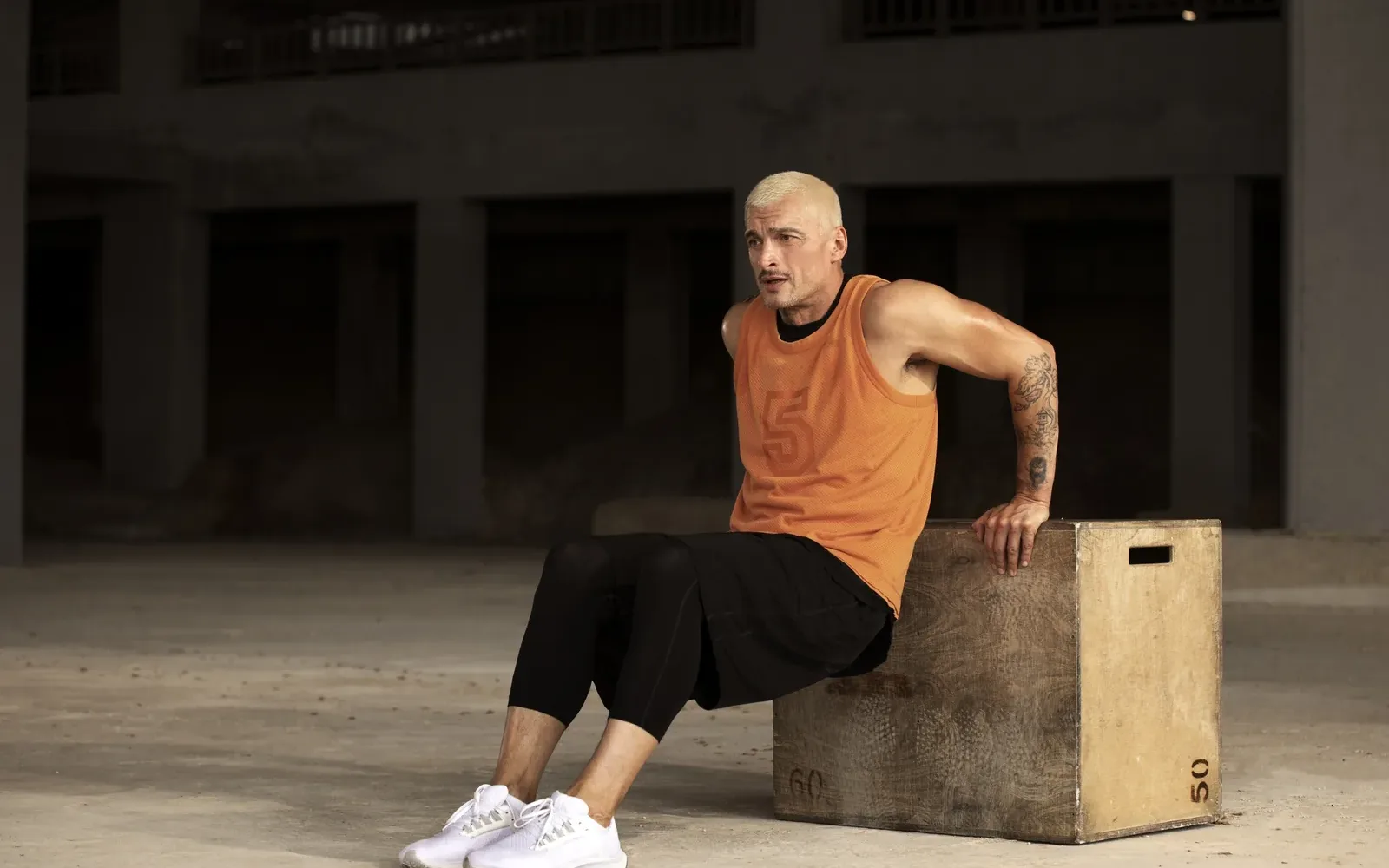 Hombre descansando sentado sobre un cajón en un gimnasio